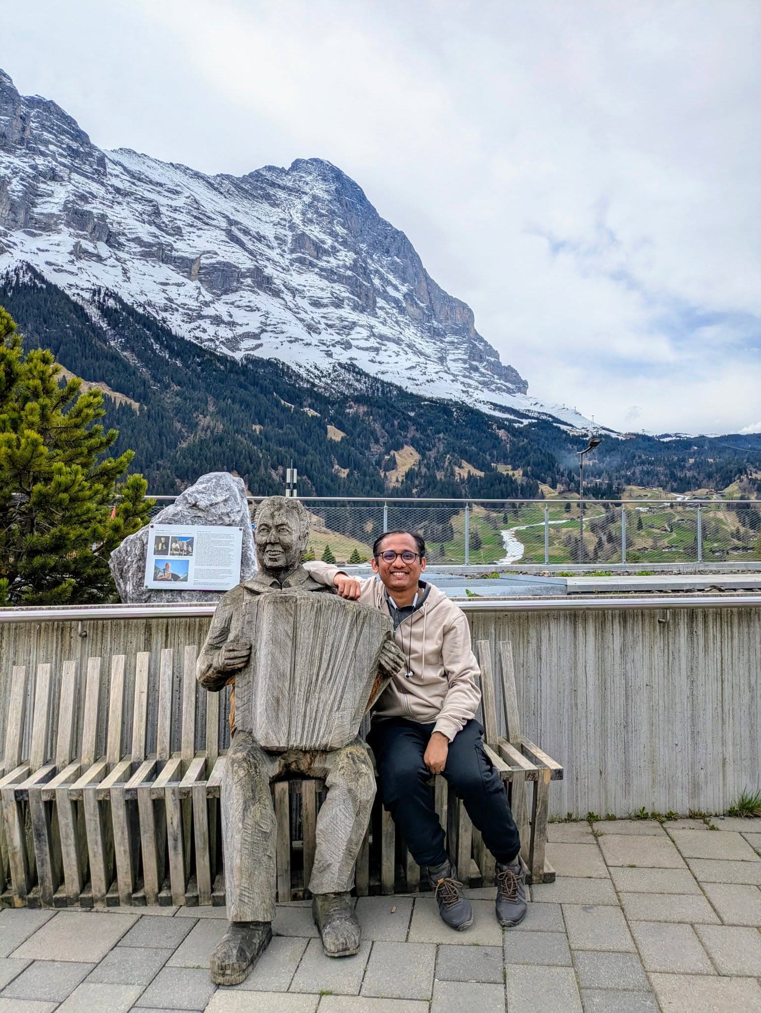 Uachash Barua seated on a terrace before a snow-covered mountain landscape